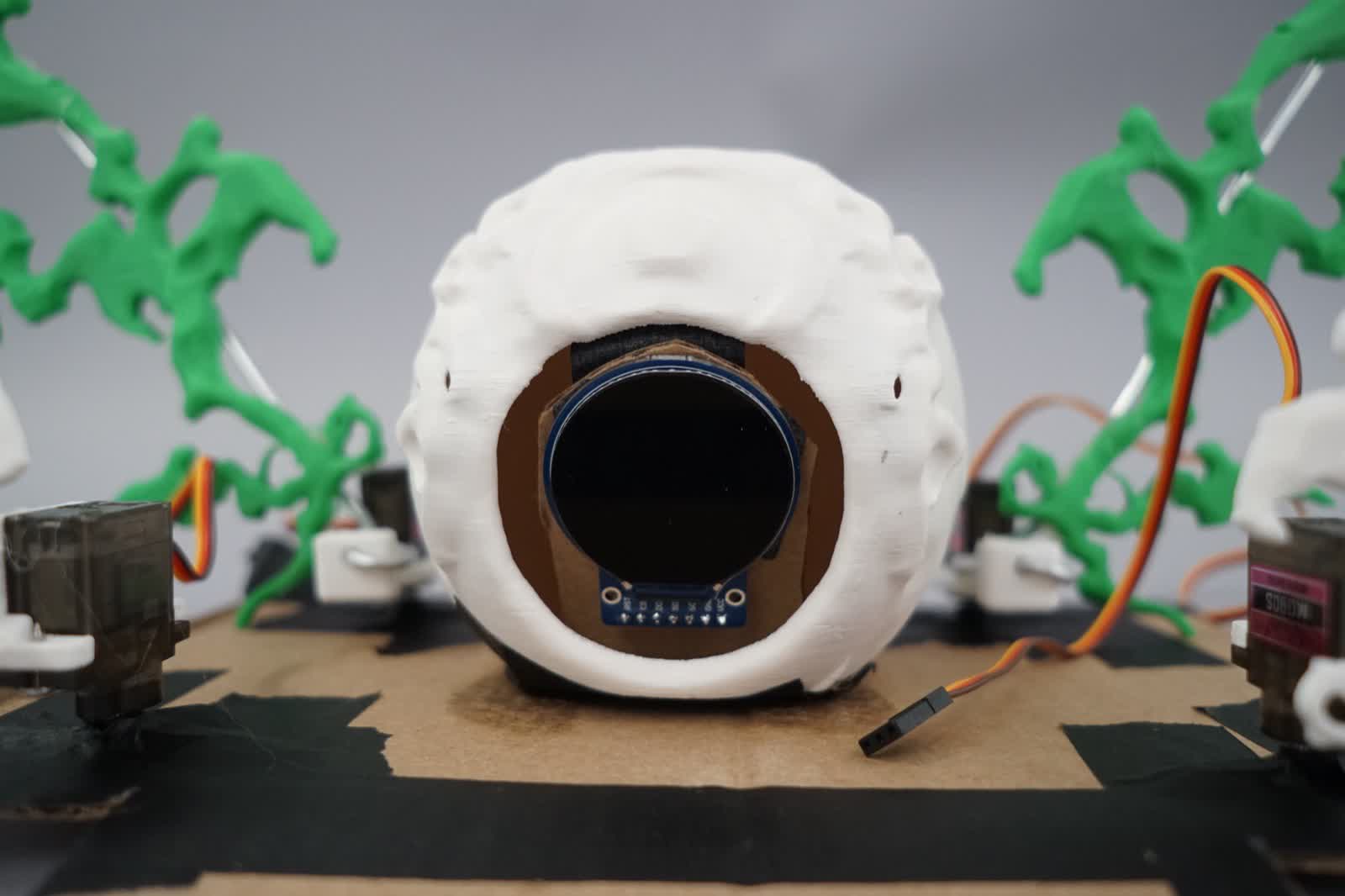 Front view showing OLED display embedded in the sphere cavity with servo motors visible